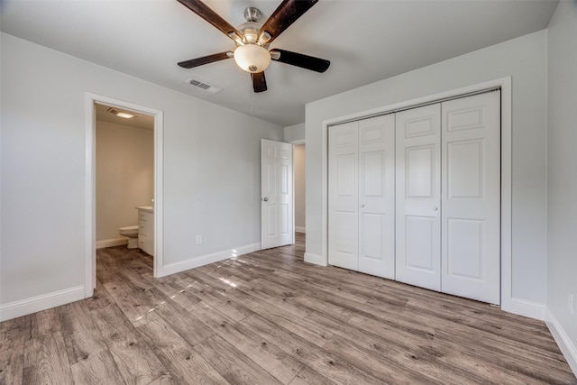 unfurnished bedroom featuring ceiling fan, ensuite bathroom, light hardwood / wood-style floors, and a closet