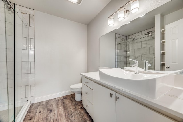 bathroom with hardwood / wood-style flooring, vanity, a shower with door, and toilet