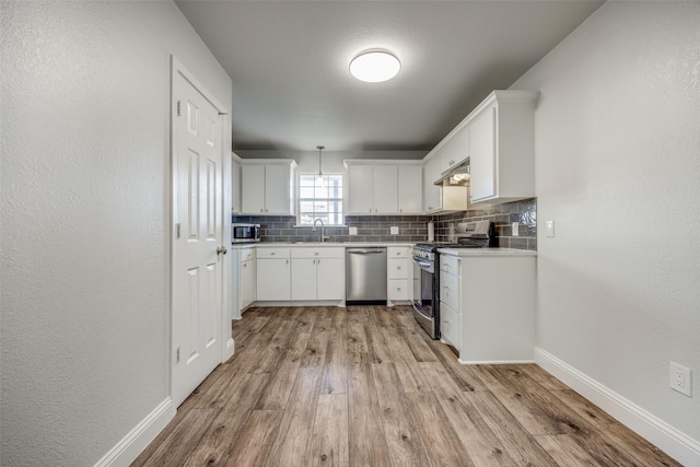 kitchen featuring appliances with stainless steel finishes, sink, white cabinets, backsplash, and light hardwood / wood-style floors