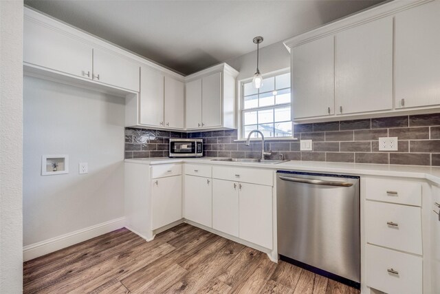 kitchen with hardwood / wood-style floors, dishwasher, sink, white cabinets, and hanging light fixtures