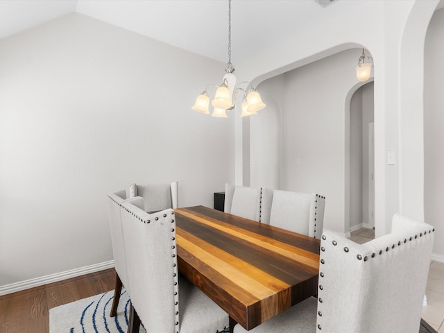 dining room featuring wood-type flooring, lofted ceiling, and a notable chandelier