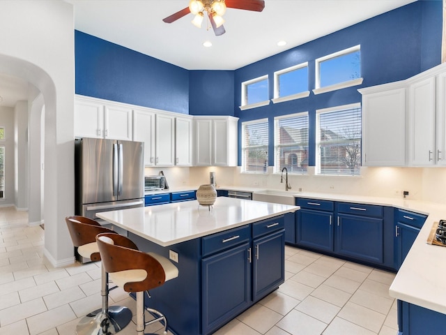 kitchen with blue cabinets, white cabinetry, a kitchen island, and sink