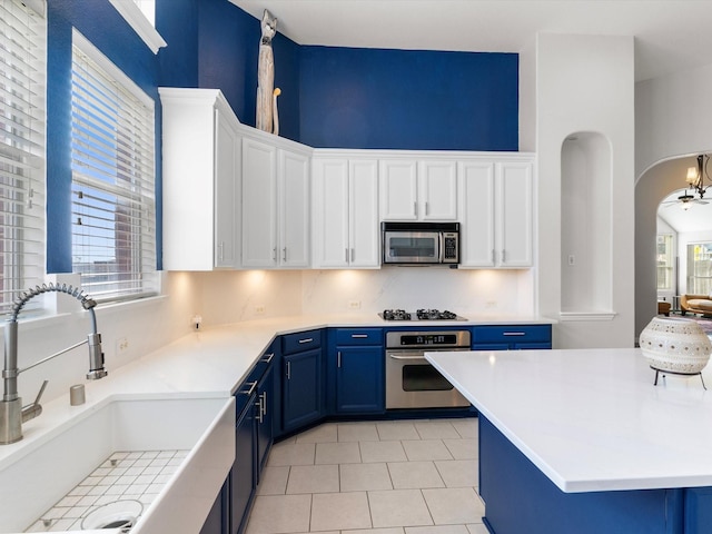 kitchen featuring sink, stainless steel appliances, white cabinets, and blue cabinetry