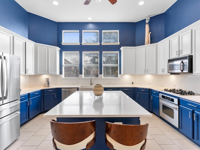 kitchen featuring white cabinetry, appliances with stainless steel finishes, a center island, and blue cabinets