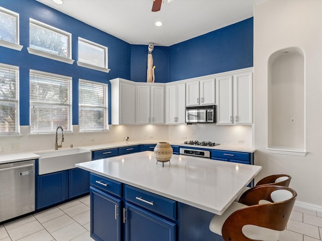 kitchen with sink, stainless steel appliances, white cabinets, and a kitchen island