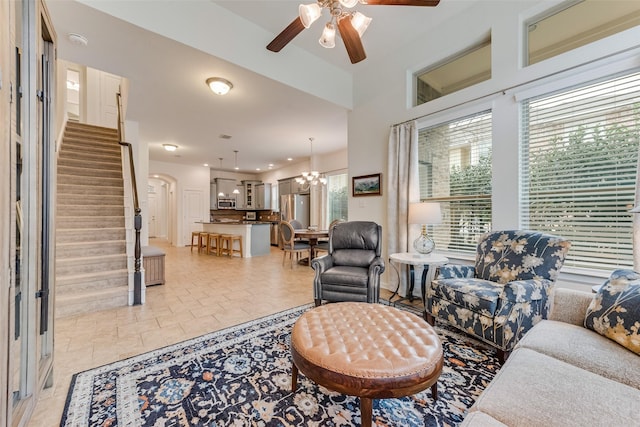 living room with light tile patterned flooring and ceiling fan with notable chandelier