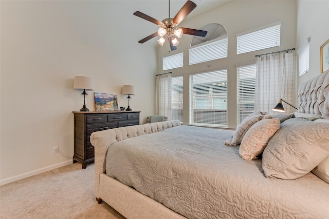 bedroom featuring light carpet, ceiling fan, and a high ceiling