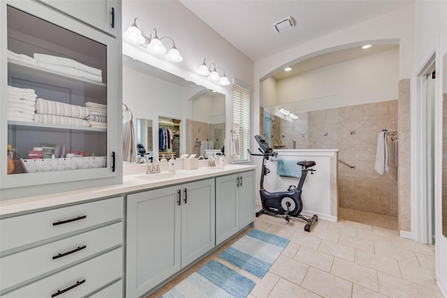 bathroom featuring tile patterned flooring, vanity, and a tile shower