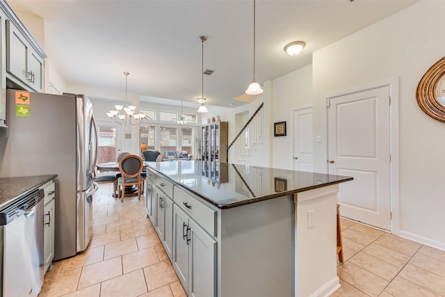 kitchen featuring gray cabinetry, dark stone counters, hanging light fixtures, a center island, and stainless steel appliances