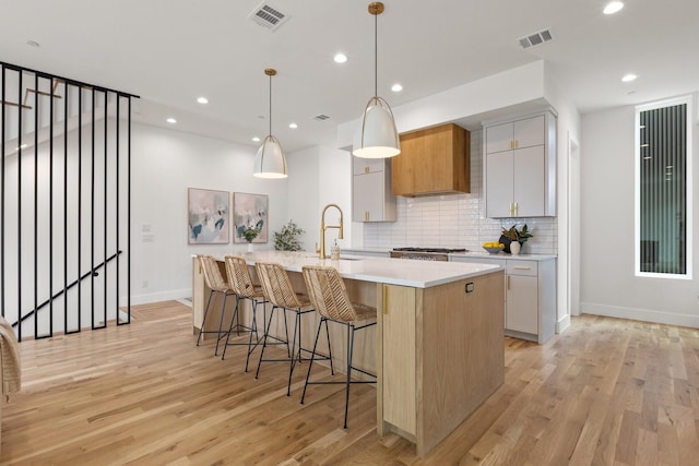 4330 Dickason Ave Unit 201, Dallas, TX 75219 - kitchen with a sink, light countertops, light wood finished floors, tasteful backsplash, and a spacious island