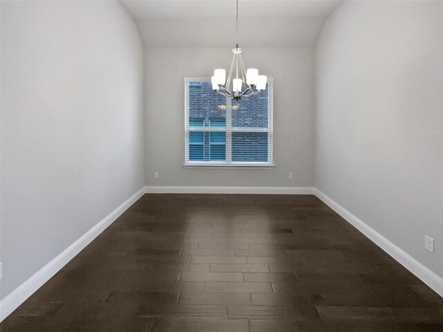 spare room with an inviting chandelier and dark hardwood / wood-style flooring