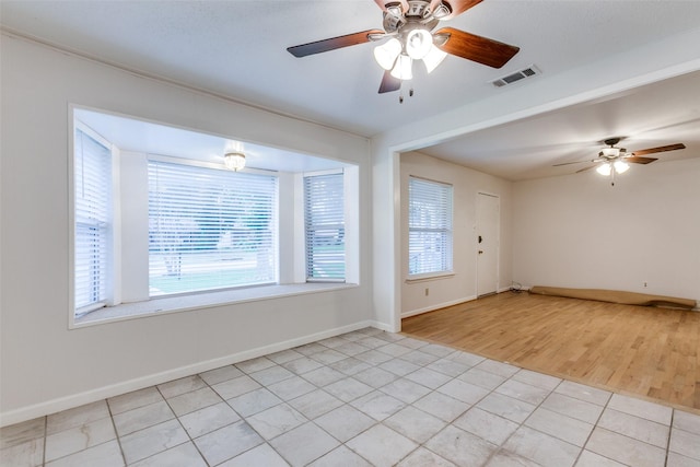 spare room featuring a wealth of natural light, ceiling fan, and light tile patterned flooring