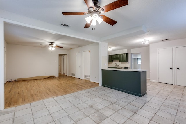 kitchen with ceiling fan, green cabinetry, kitchen peninsula, and light tile patterned floors