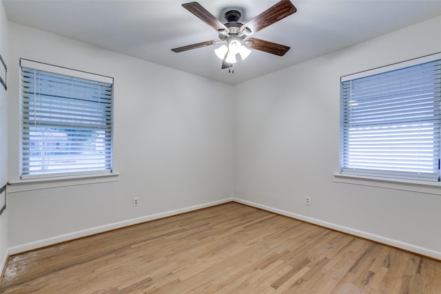 empty room with ceiling fan, plenty of natural light, and light hardwood / wood-style flooring