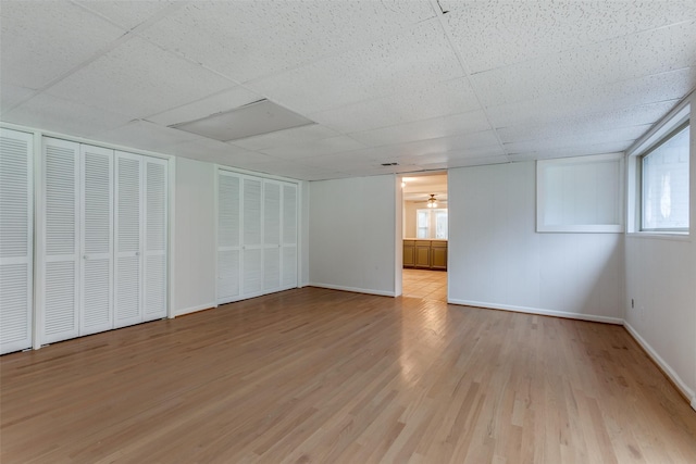 unfurnished room with a drop ceiling and light wood-type flooring