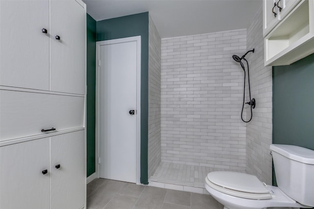 bathroom featuring tile patterned floors, toilet, and a tile shower