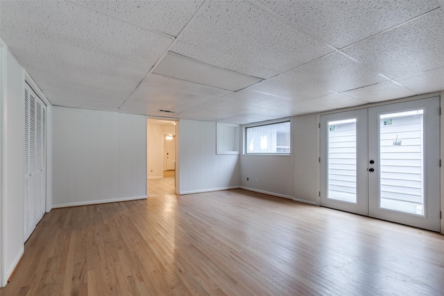 interior space featuring a drop ceiling, light hardwood / wood-style floors, and french doors