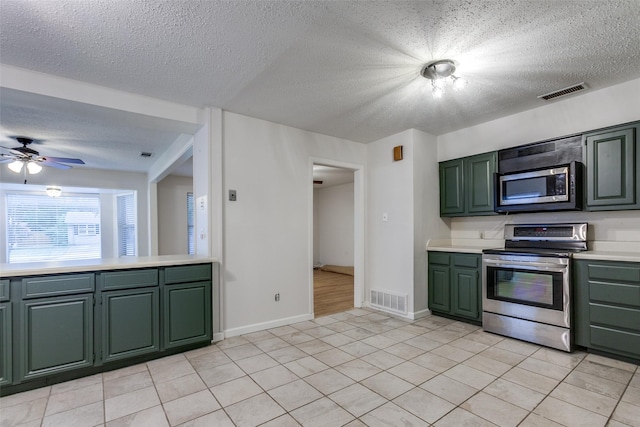 kitchen featuring green cabinets, light tile patterned floors, ceiling fan, stainless steel appliances, and a textured ceiling