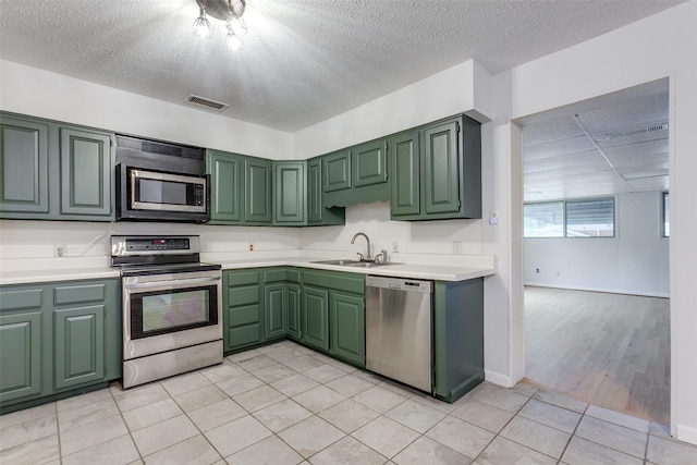 kitchen with light tile patterned flooring, green cabinetry, appliances with stainless steel finishes, and sink