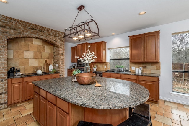 kitchen with sink, hanging light fixtures, backsplash, a center island, and a kitchen bar