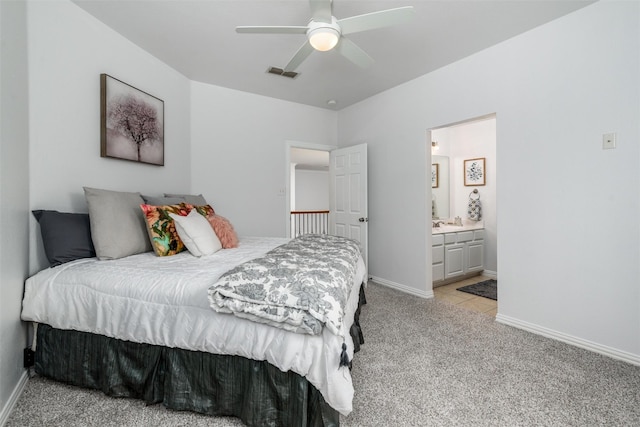 bedroom with ceiling fan, connected bathroom, and light carpet