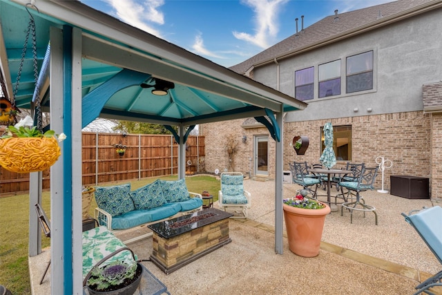 view of patio with a gazebo, ceiling fan, and an outdoor living space with a fire pit