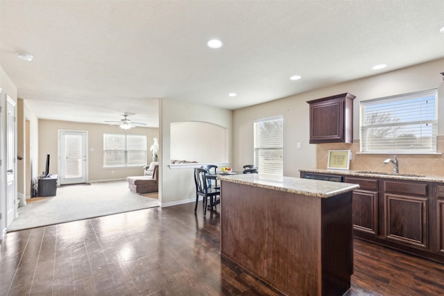 kitchen featuring sink, dark brown cabinets, dark hardwood / wood-style floors, a kitchen island, and decorative backsplash