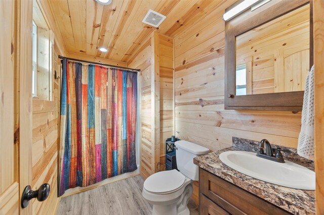 kitchen featuring sink, appliances with stainless steel finishes, wooden walls, kitchen peninsula, and light hardwood / wood-style floors