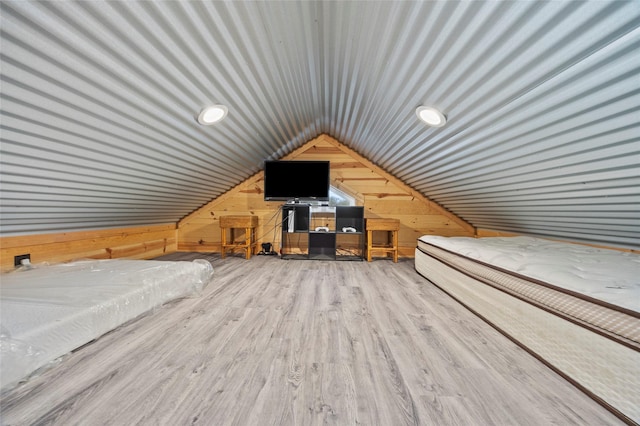 additional living space with vaulted ceiling, wood-type flooring, and wood walls