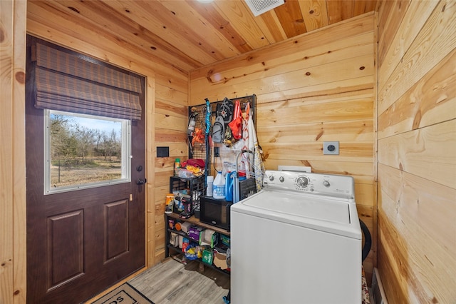 clothes washing area with hardwood / wood-style flooring, washer / dryer, wood ceiling, and wood walls