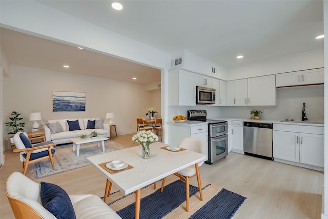 kitchen with sink, light hardwood / wood-style floors, white cabinets, and appliances with stainless steel finishes