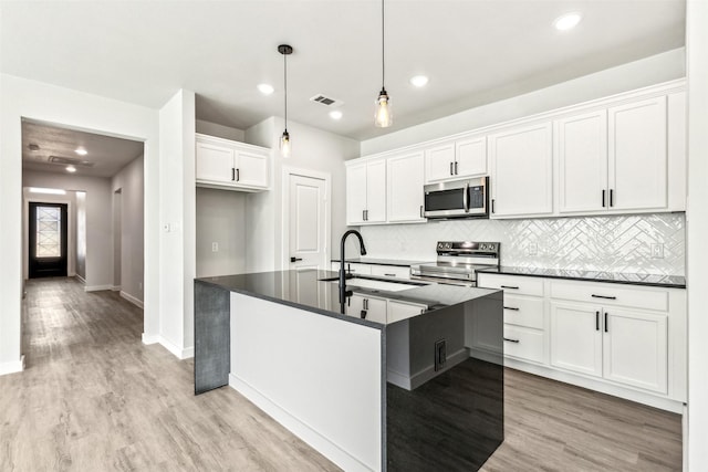 kitchen with sink, white cabinetry, light wood-type flooring, pendant lighting, and stainless steel appliances