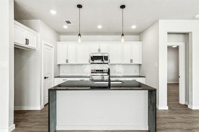 kitchen featuring dark hardwood / wood-style floors, pendant lighting, white cabinets, a kitchen island with sink, and stainless steel appliances