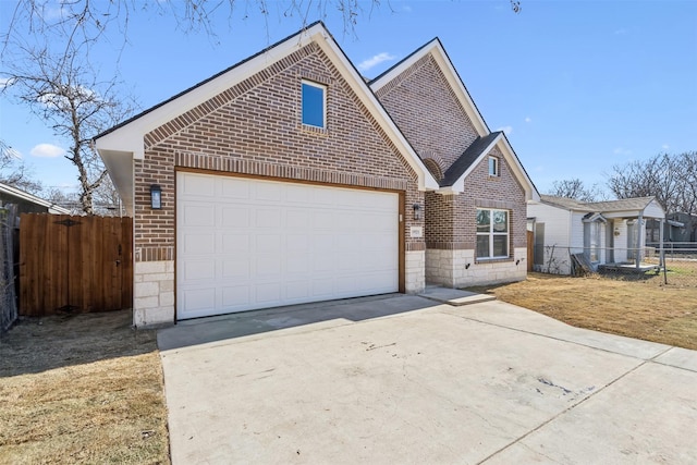 view of front of house with brick siding, driveway, a garage, and fence