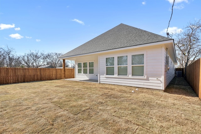 back of house with a yard, a fenced backyard, central AC, and roof with shingles