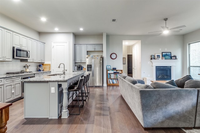 kitchen with a kitchen bar, stainless steel appliances, sink, and an island with sink