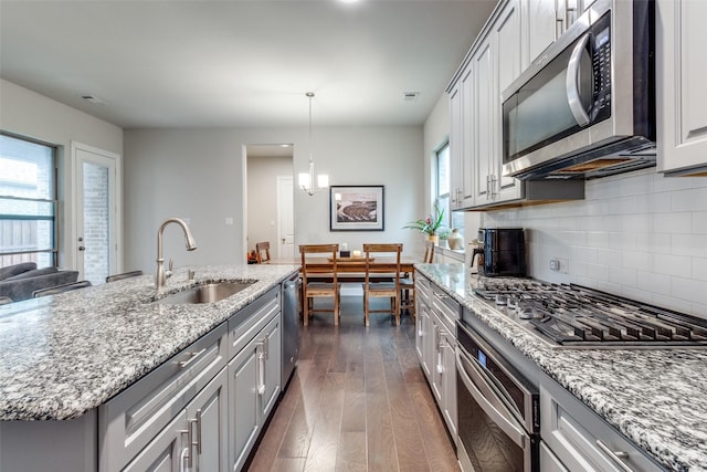 kitchen with sink, a center island with sink, dark hardwood / wood-style floors, stainless steel appliances, and decorative backsplash