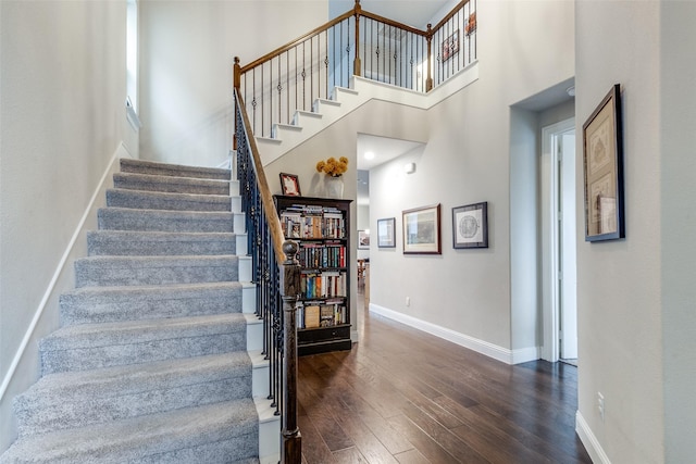 stairs with a towering ceiling and hardwood / wood-style floors