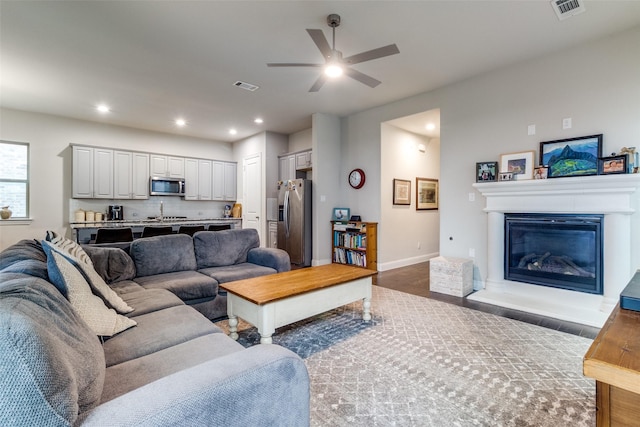 living room featuring ceiling fan, sink, and hardwood / wood-style floors