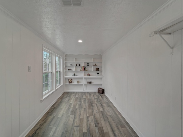 interior space featuring hardwood / wood-style flooring, built in features, ornamental molding, and a textured ceiling