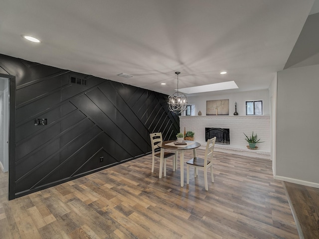 dining space with wood-type flooring, a fireplace, and a notable chandelier