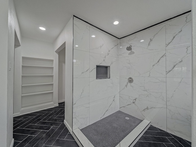 bathroom featuring a tile shower and built in shelves