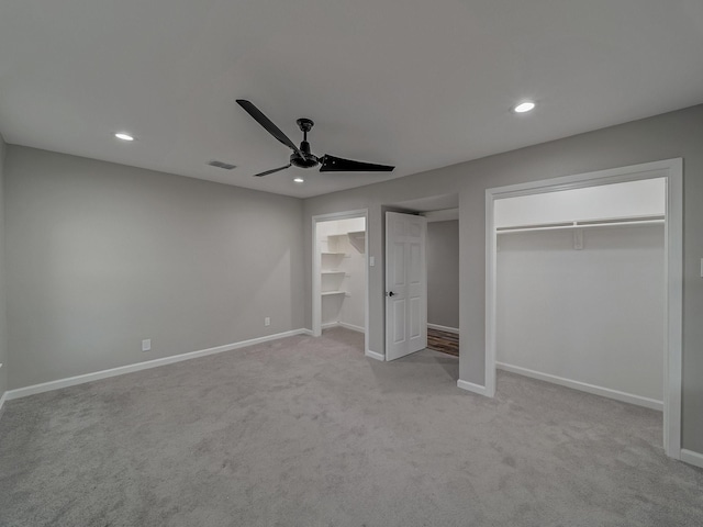 unfurnished bedroom featuring two closets, light colored carpet, and ceiling fan