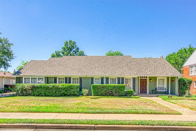 ranch-style home featuring covered porch and a front lawn