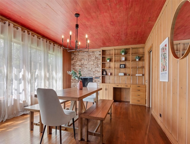 dining area featuring dark wood-type flooring, a notable chandelier, wood walls, and wooden ceiling