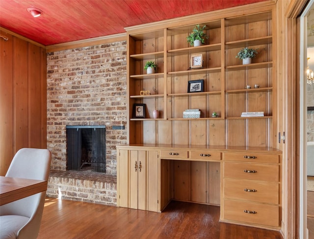 interior space with dark hardwood / wood-style flooring, a fireplace, ornamental molding, and wooden walls