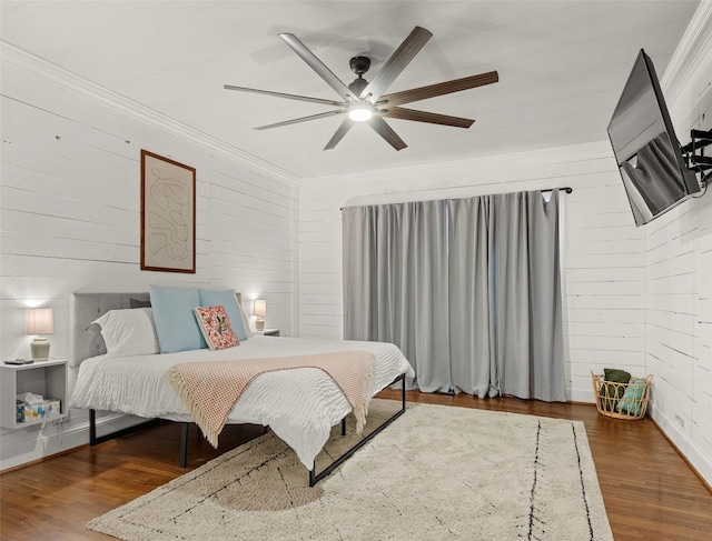 bedroom featuring crown molding, ceiling fan, hardwood / wood-style floors, and wood walls