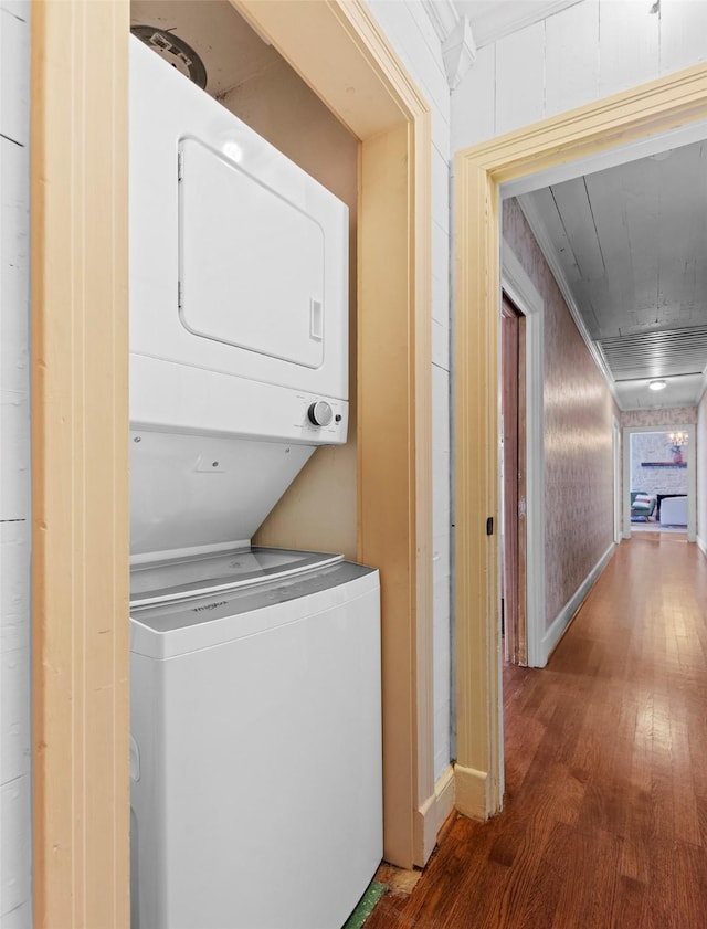 washroom featuring stacked washer and dryer, wood-type flooring, and ornamental molding