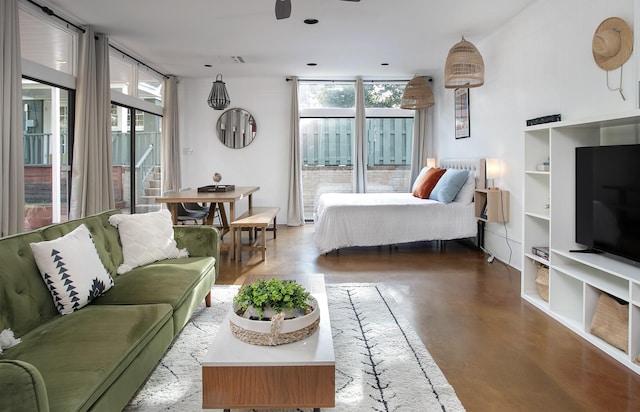 bedroom featuring access to exterior, a wall of windows, and concrete floors