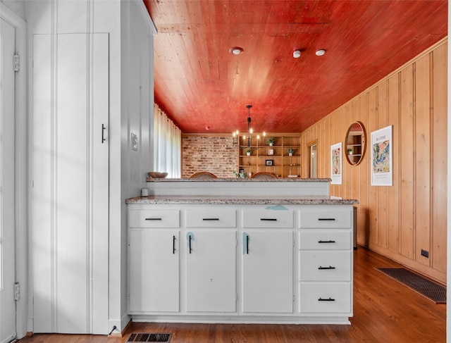 kitchen with white cabinetry, wood ceiling, light stone counters, pendant lighting, and hardwood / wood-style floors